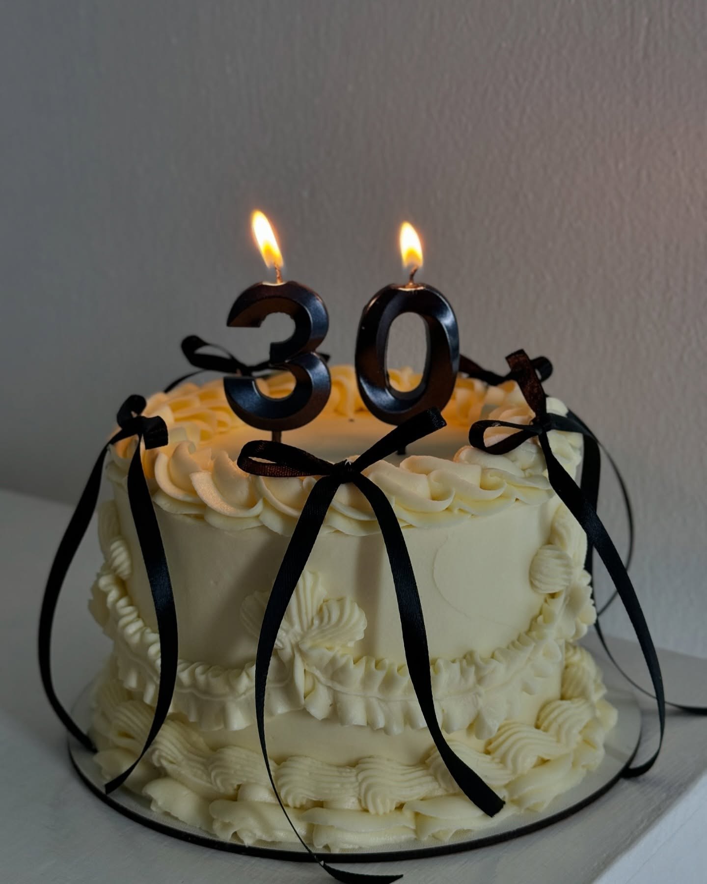 Світлий торт із чорними стрічками та цифрою 30